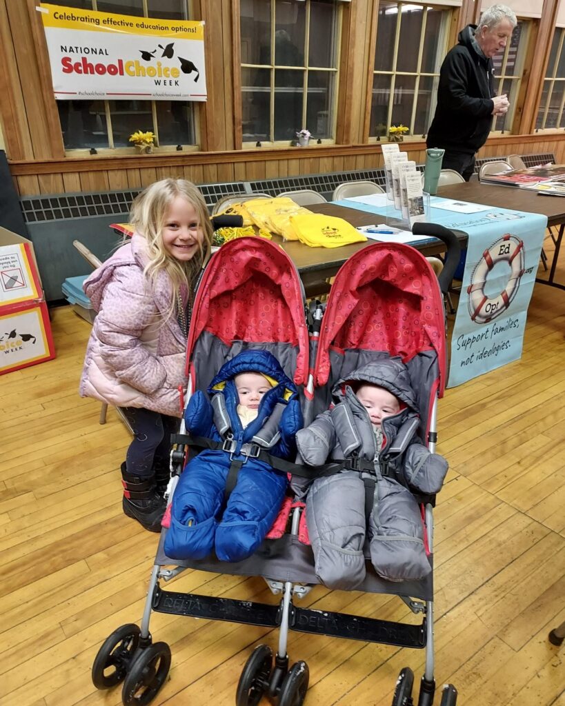 Young girl and two infants in a twin stroller