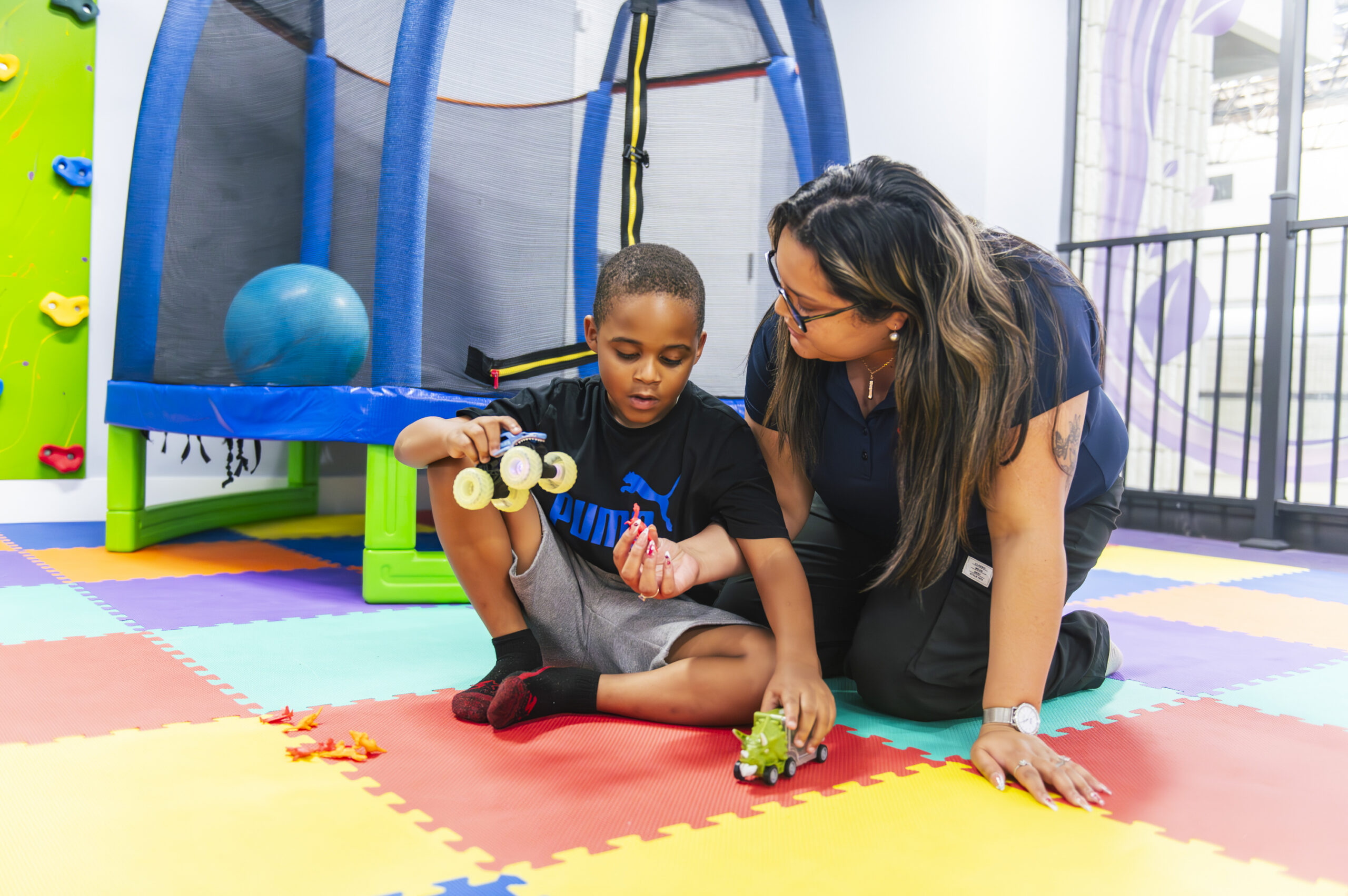 Woman and child on a colorful mat playing.