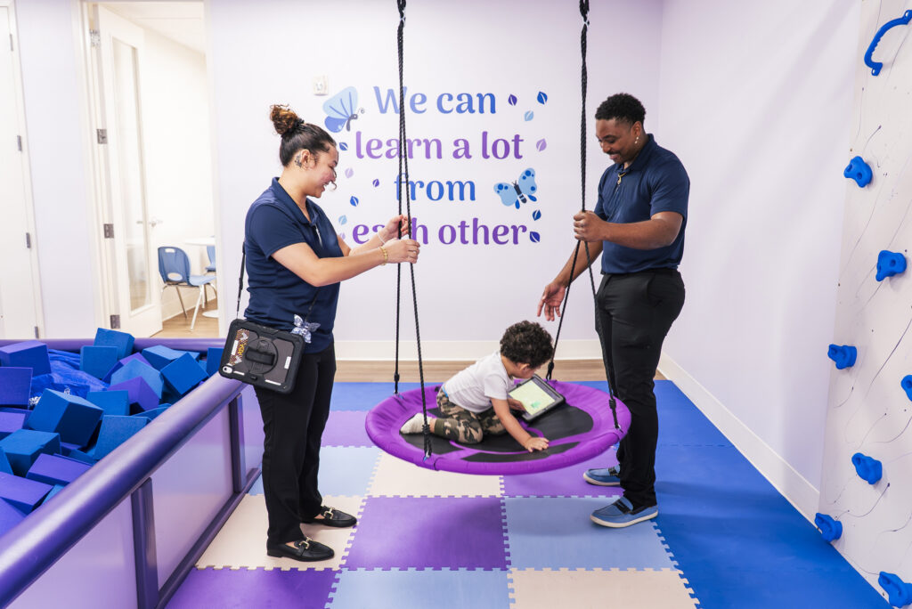 Man and woman holding a swing that a child is sitting on