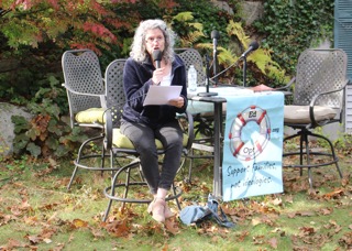 Jody Underwood speaks into a microphone while holding notes at a table displaying an EdOpt sign.
