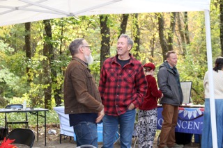 Guests chat beside an information table under the canopy at EdOpt’s 2026 Donor and Volunteer Appreciation Gathering.
