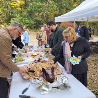 Guests serve themselves from a whole roasted pig at the outdoor buffet at EdOpt’s 2026 Donor and Volunteer Appreciation Gathering.