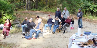 Guests sit in a row of folding chairs outdoors, with others standing behind them at EdOpt’s 2026 Donor and Volunteer Appreciation Gathering.