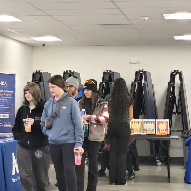 Young visitors stand near a dice probability activity and the New Hampshire Career Academy display.
