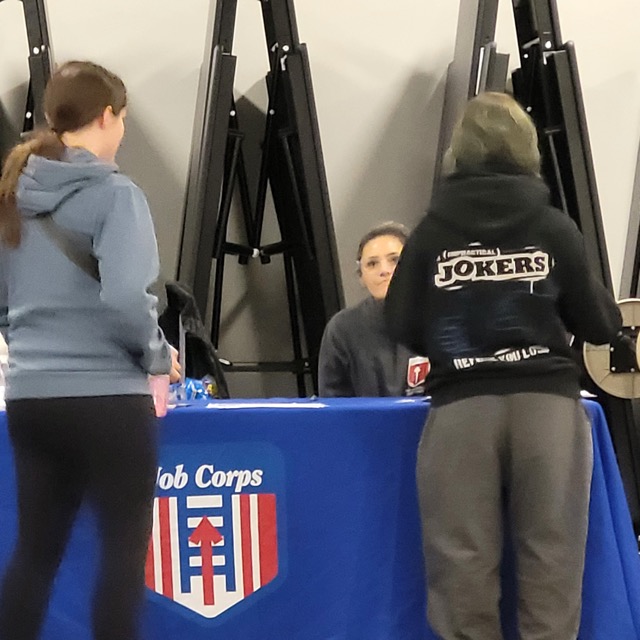 Two visitors speak with a representative behind the New Hampshire Job Corps table.